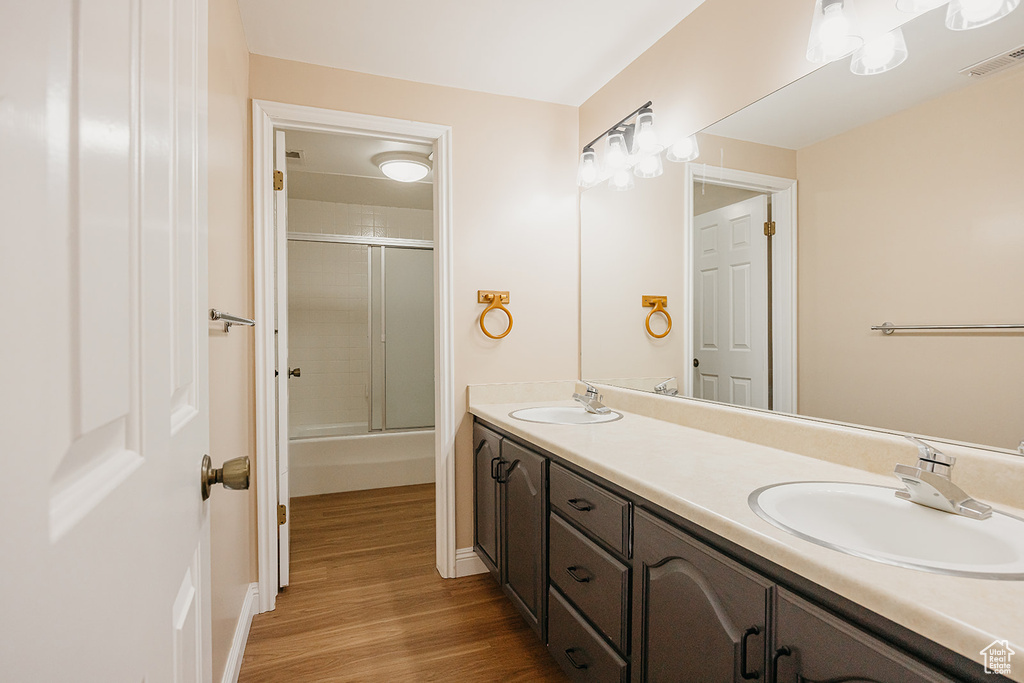 Full bath featuring a sink, double vanity, visible vents, and wood finished floors