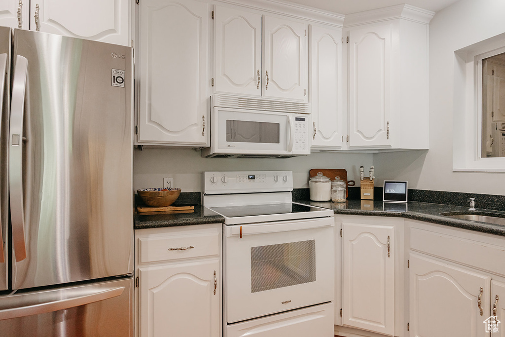 Kitchen featuring a sink, white appliances, and white cabinets