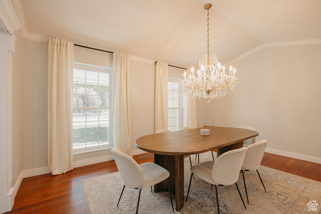 Dining room featuring vaulted ceiling, a chandelier, baseboards, and hardwood / wood-style flooring