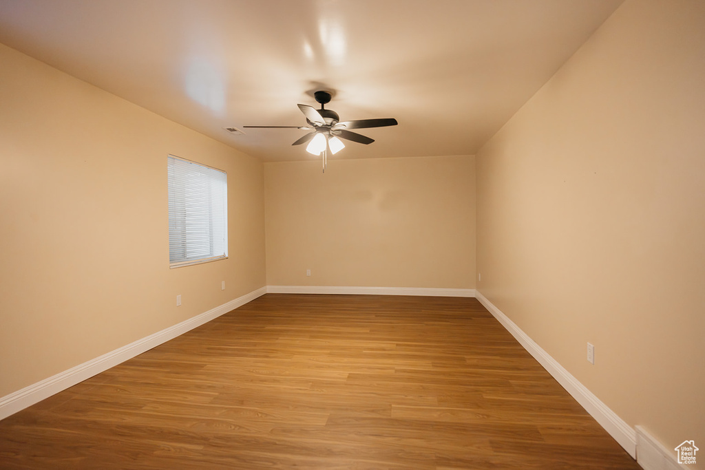 Empty room featuring light wood finished floors, baseboards, and a ceiling fan
