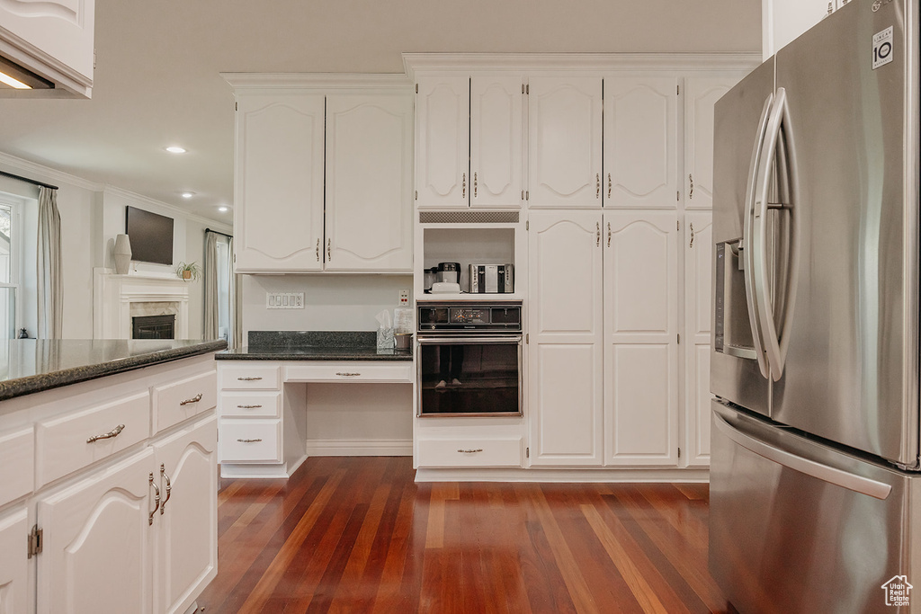 Kitchen featuring white cabinetry, oven, stainless steel refrigerator with ice dispenser, and dark wood-style floors