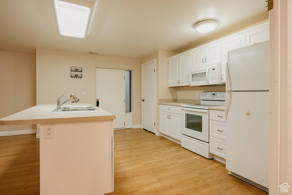 Kitchen with light wood-style flooring, white appliances, a sink, white cabinetry, and light countertops