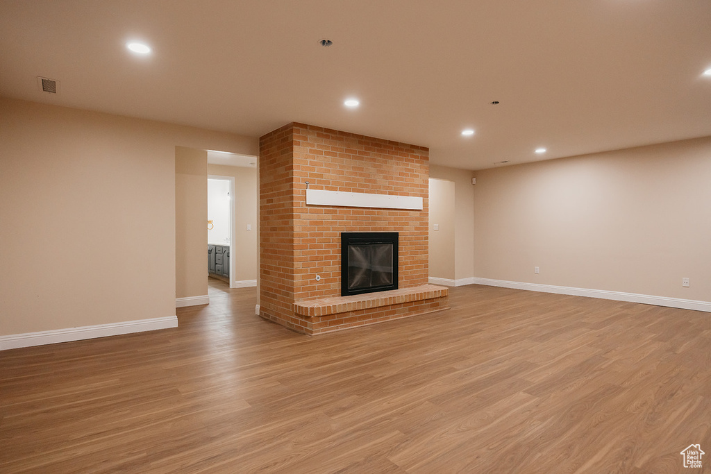 Unfurnished living room featuring light wood-style flooring, recessed lighting, baseboards, visible vents, and a fireplace