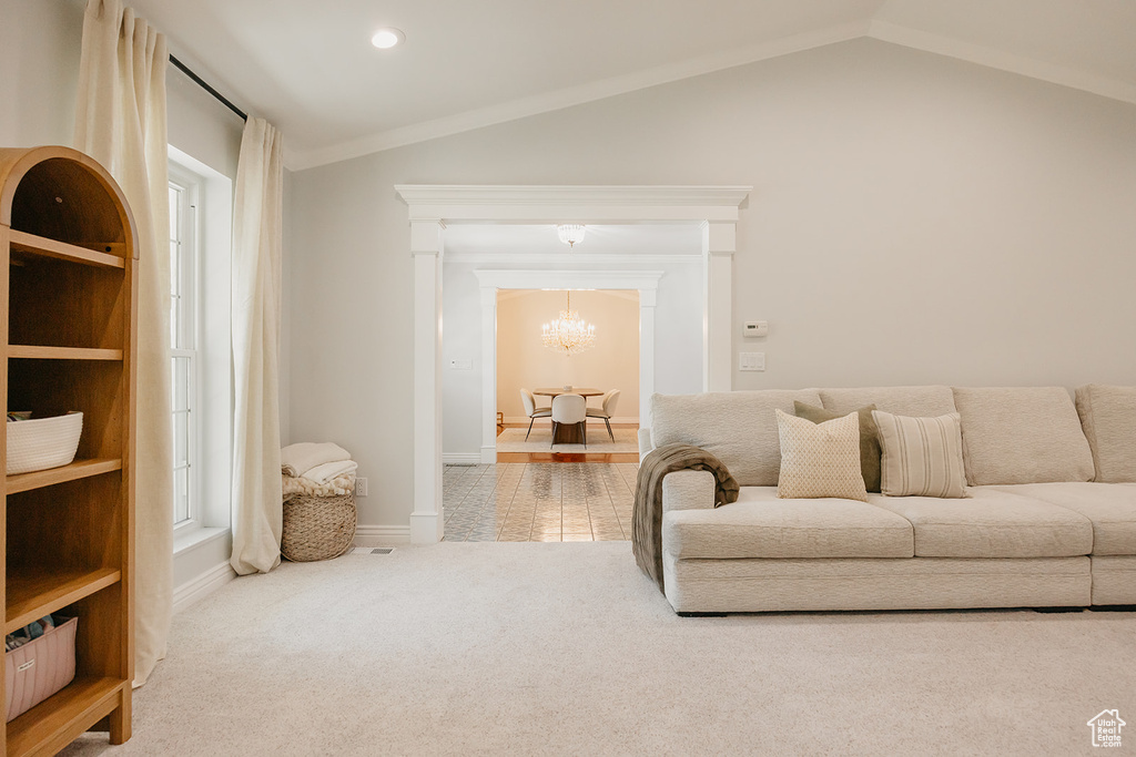 Living room featuring baseboards, a chandelier, carpet, and vaulted ceiling