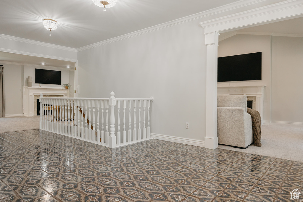 Carpeted spare room with a fireplace, crown molding, and baseboards