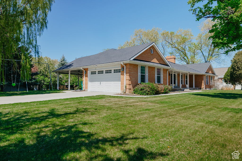 Single story home with an attached garage, a chimney, concrete driveway, a front yard, and brick siding