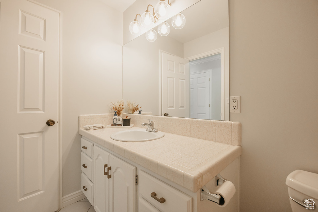 Half bath featuring toilet, tile patterned floors, and vanity