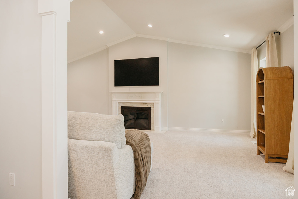 Living area with recessed lighting, crown molding, baseboards, light colored carpet, and a high end fireplace