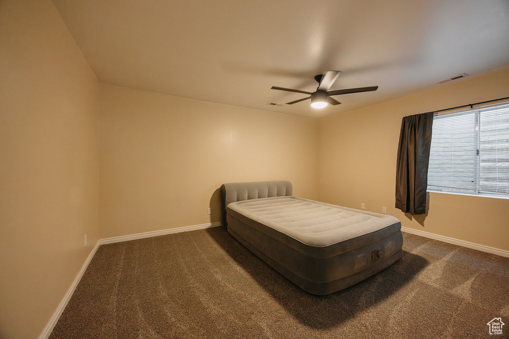 Bedroom with ceiling fan, dark colored carpet, baseboards, and visible vents