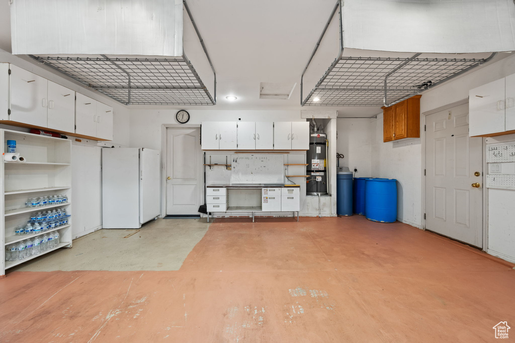 Garage featuring secured water heater and freestanding refrigerator