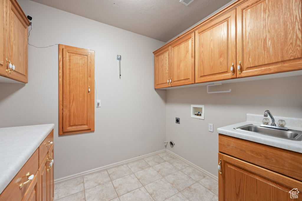 Washroom featuring cabinet space, hookup for a washing machine, hookup for an electric dryer, baseboards, and light tile patterned flooring