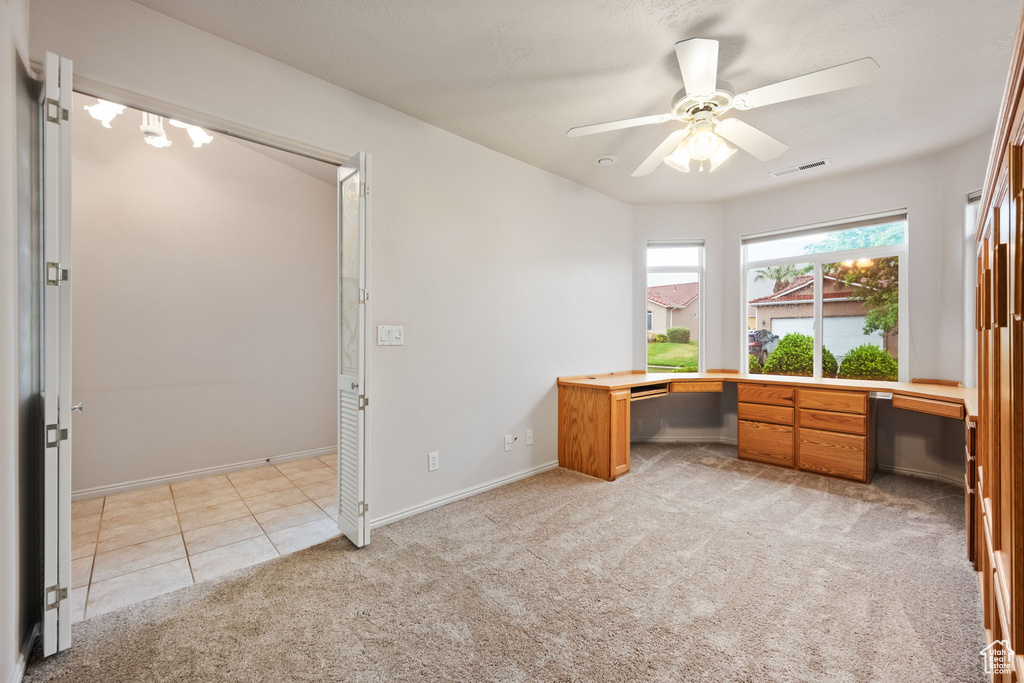 Unfurnished office featuring ceiling fan, light colored carpet, and baseboards