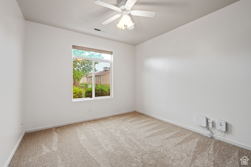 Carpeted empty room with baseboards and a ceiling fan