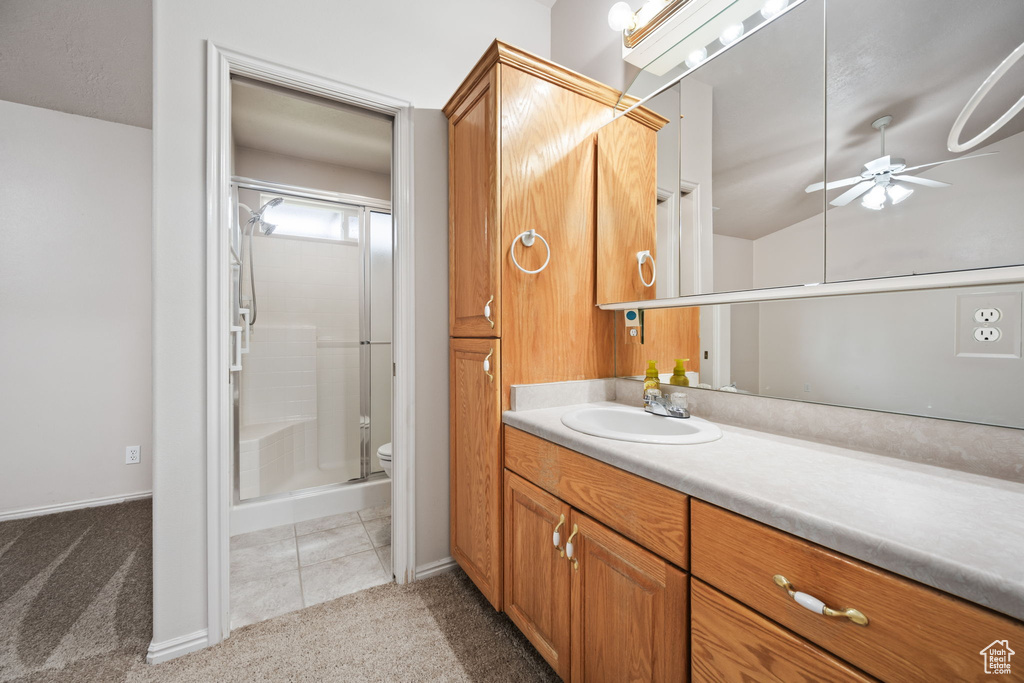 Bathroom with ceiling fan, vanity, a stall shower, toilet, and baseboards