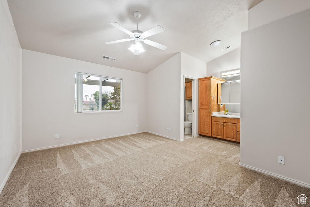 Unfurnished bedroom with light carpet, lofted ceiling, baseboards, connected bathroom, and a sink