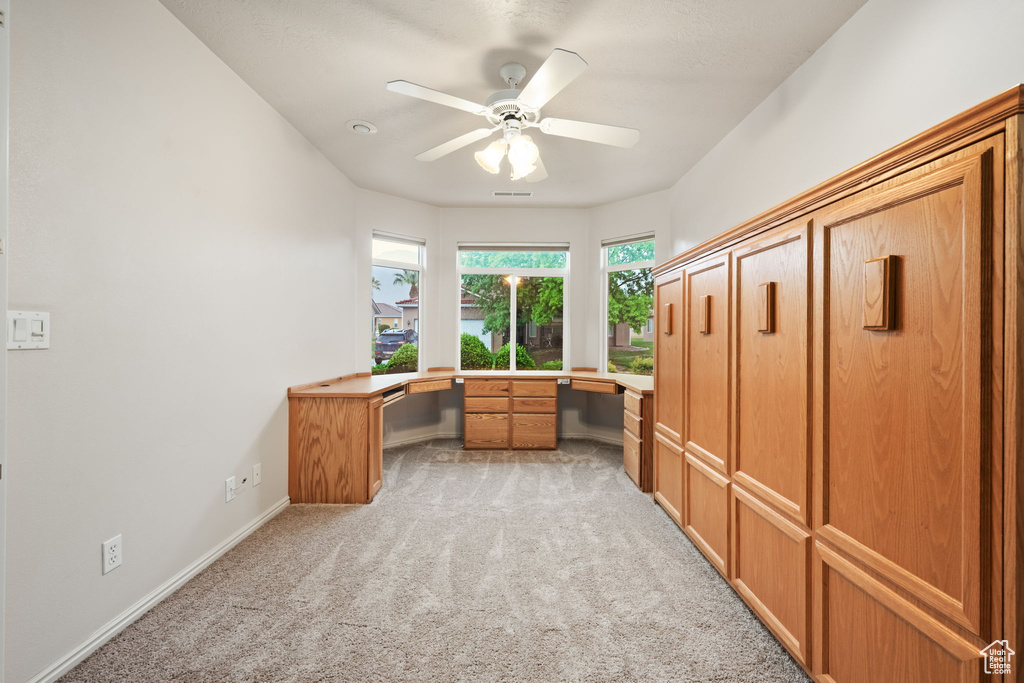 Unfurnished office with light carpet, ceiling fan, and baseboards