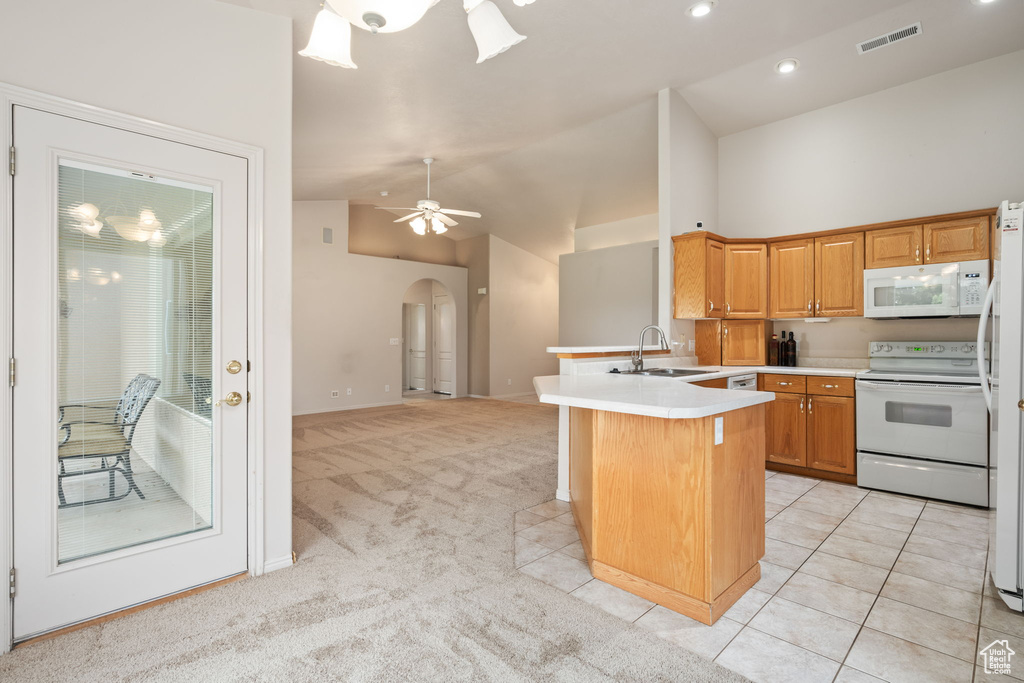 Kitchen featuring white appliances, a sink, arched walkways, a peninsula, and light countertops