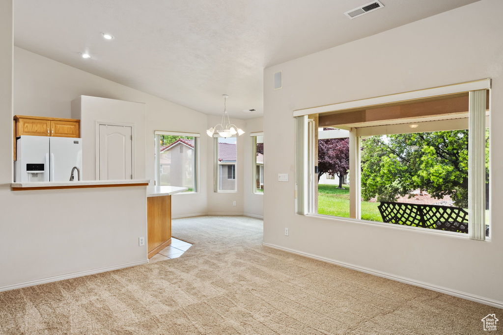 Unfurnished living room featuring a chandelier, light carpet, baseboards, vaulted ceiling, and recessed lighting