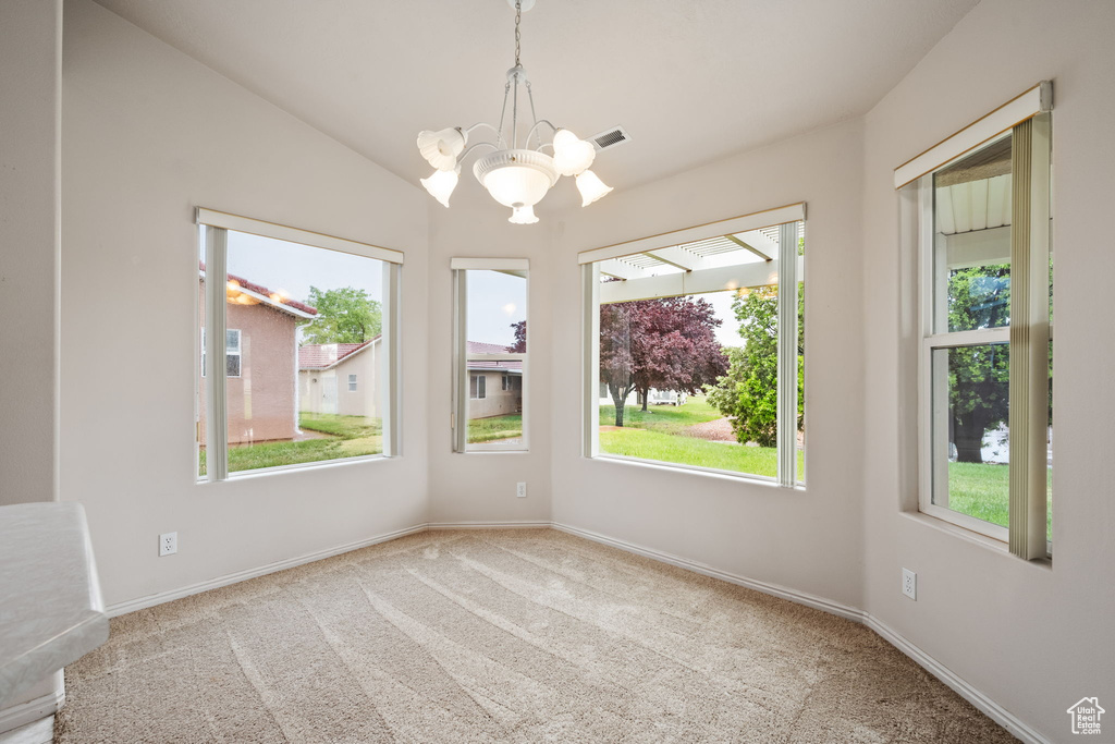 Carpeted spare room featuring a chandelier, baseboards, and vaulted ceiling