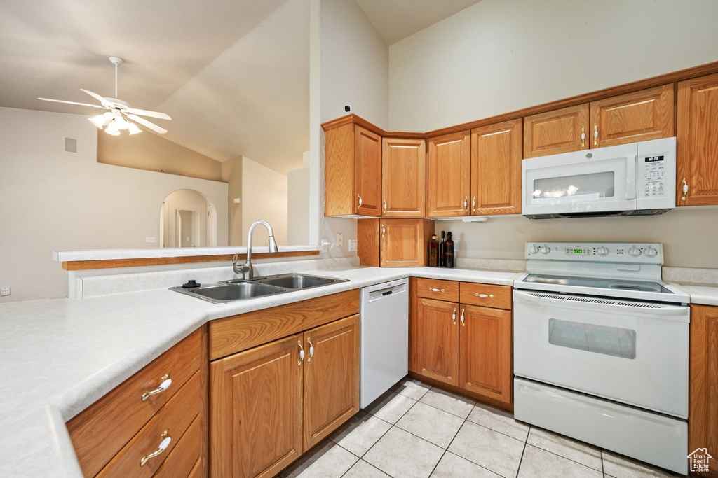 Kitchen featuring white appliances, a sink, vaulted ceiling, light tile patterned floors, and light countertops