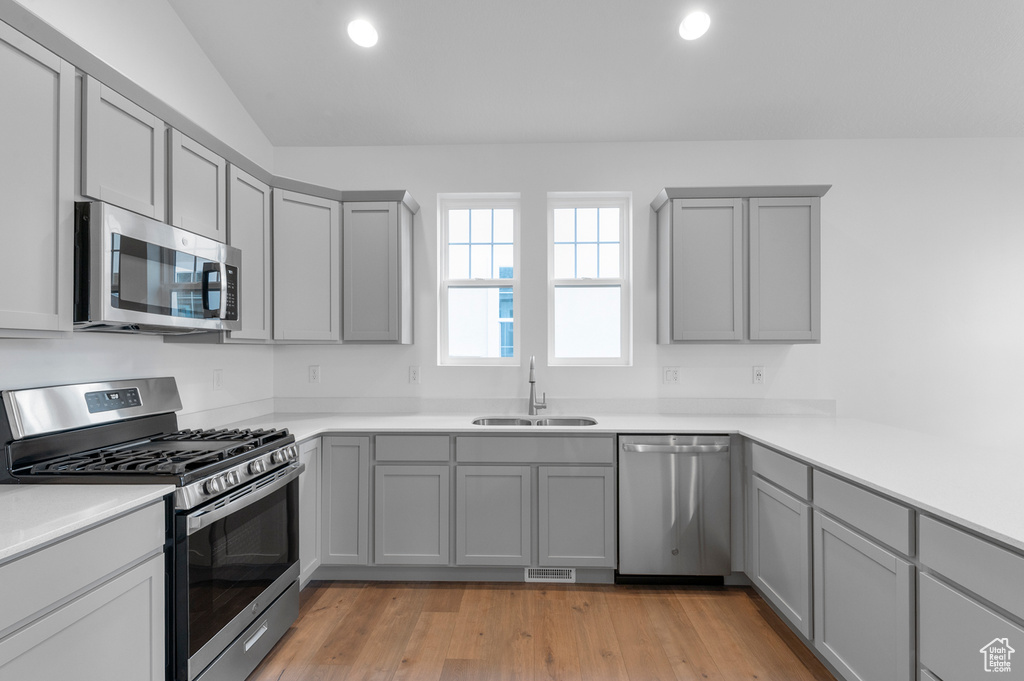 Kitchen featuring appliances with stainless steel finishes, gray cabinetry, a sink, recessed lighting, and light wood-type flooring