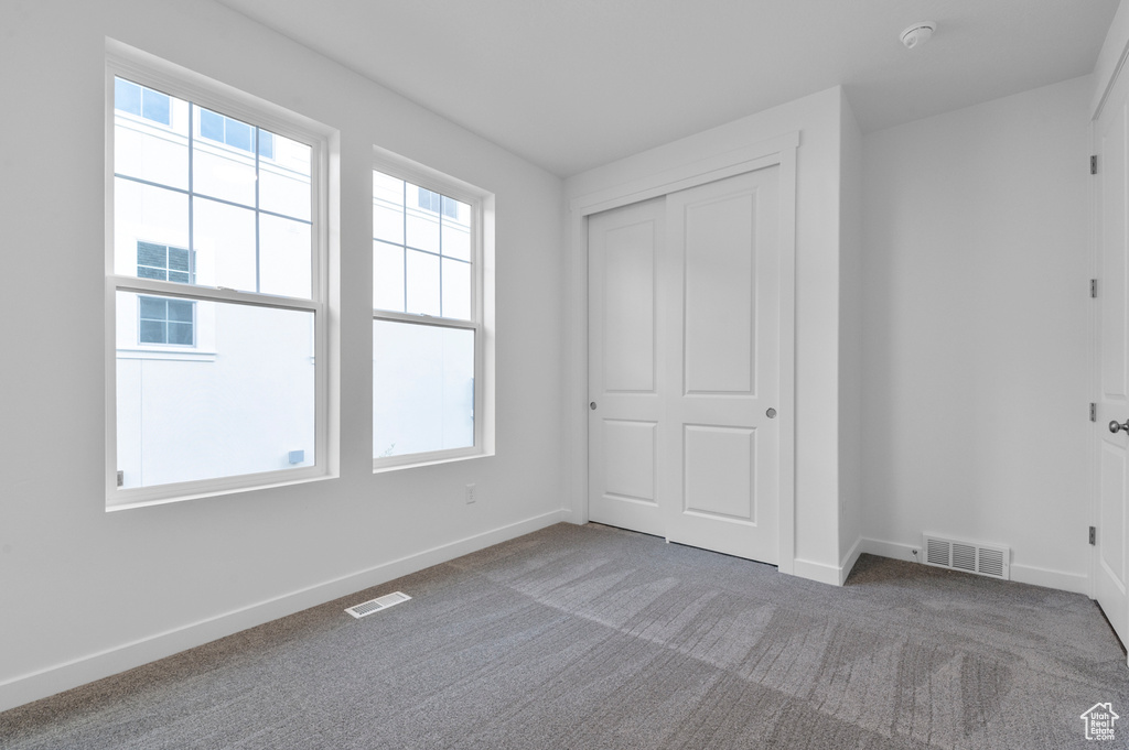 Unfurnished bedroom with baseboards, carpet, and a closet