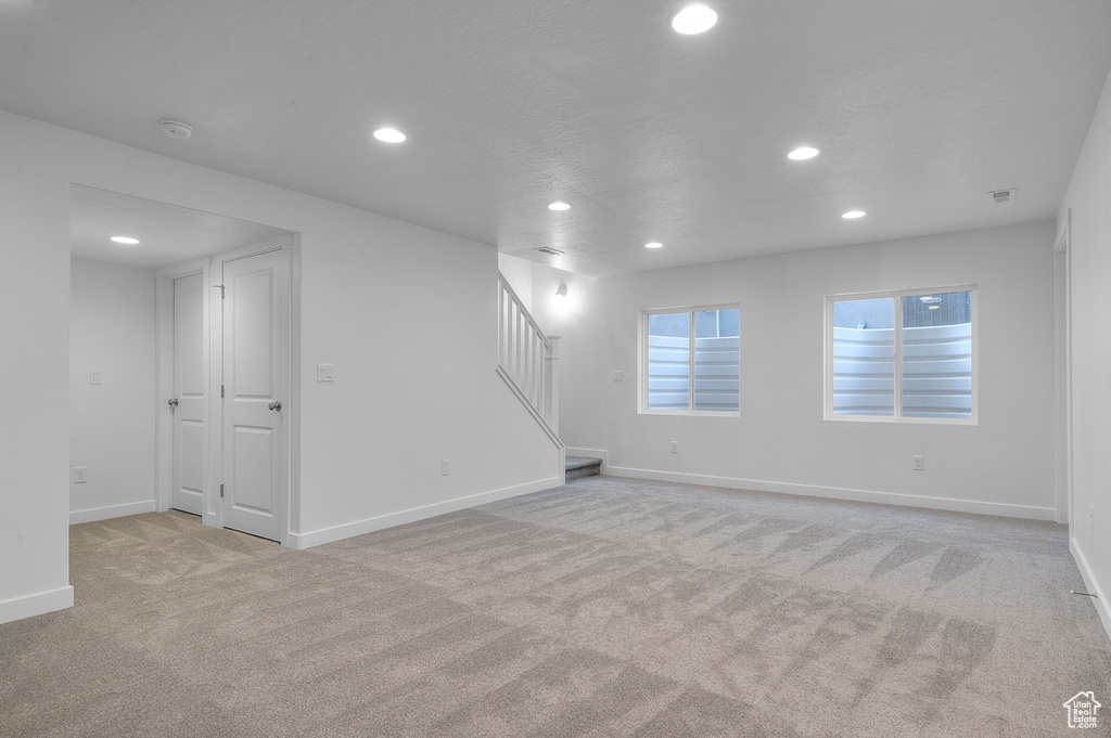 Below grade area featuring recessed lighting, stairway, light colored carpet, and baseboards