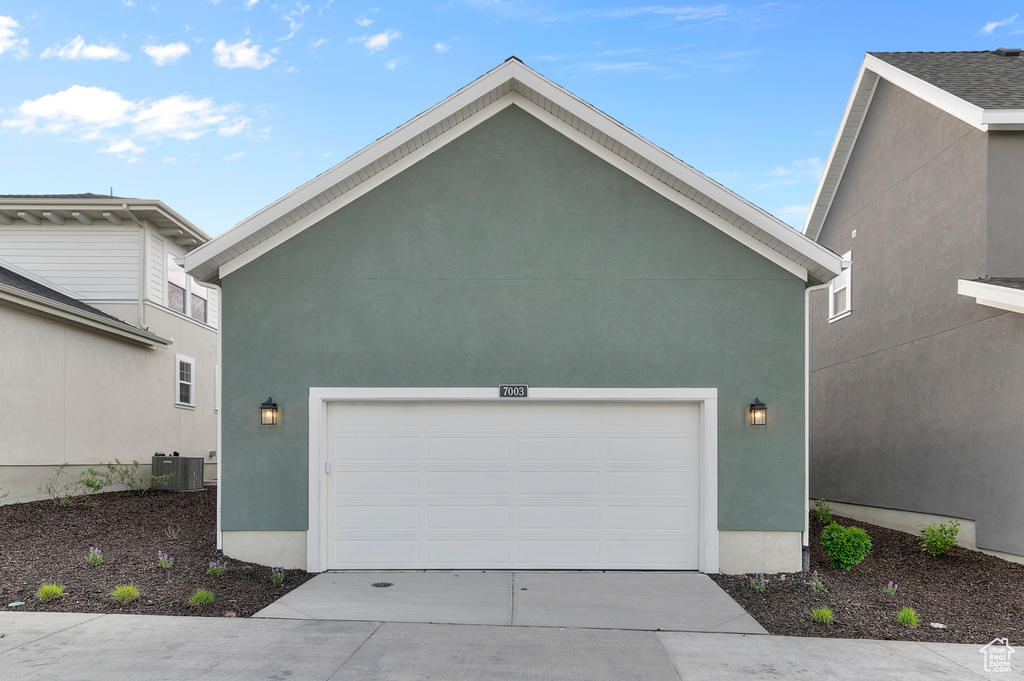 Garage with central AC unit and driveway