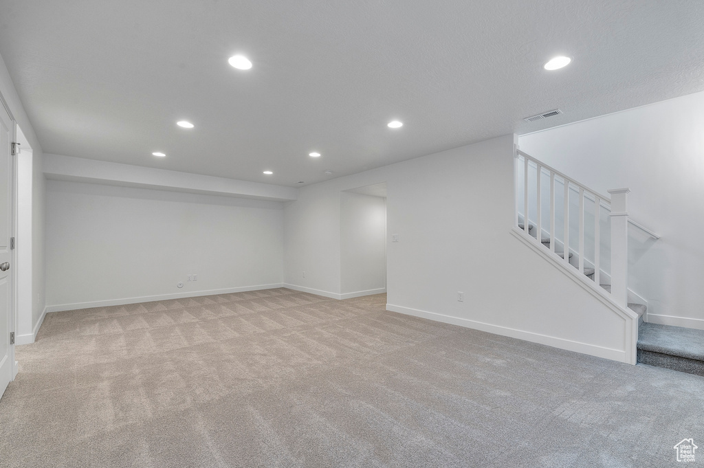 Unfurnished living room featuring recessed lighting, light carpet, stairs, and baseboards
