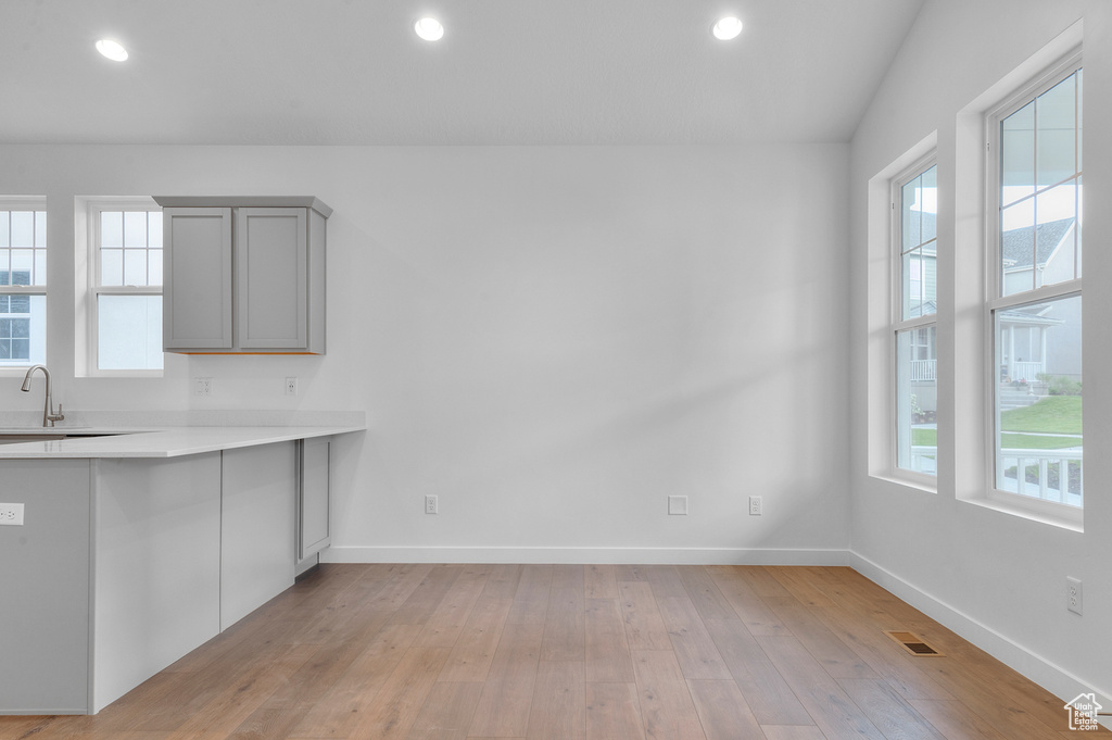 Kitchen featuring gray cabinets, light countertops, baseboards, light wood-type flooring, and recessed lighting