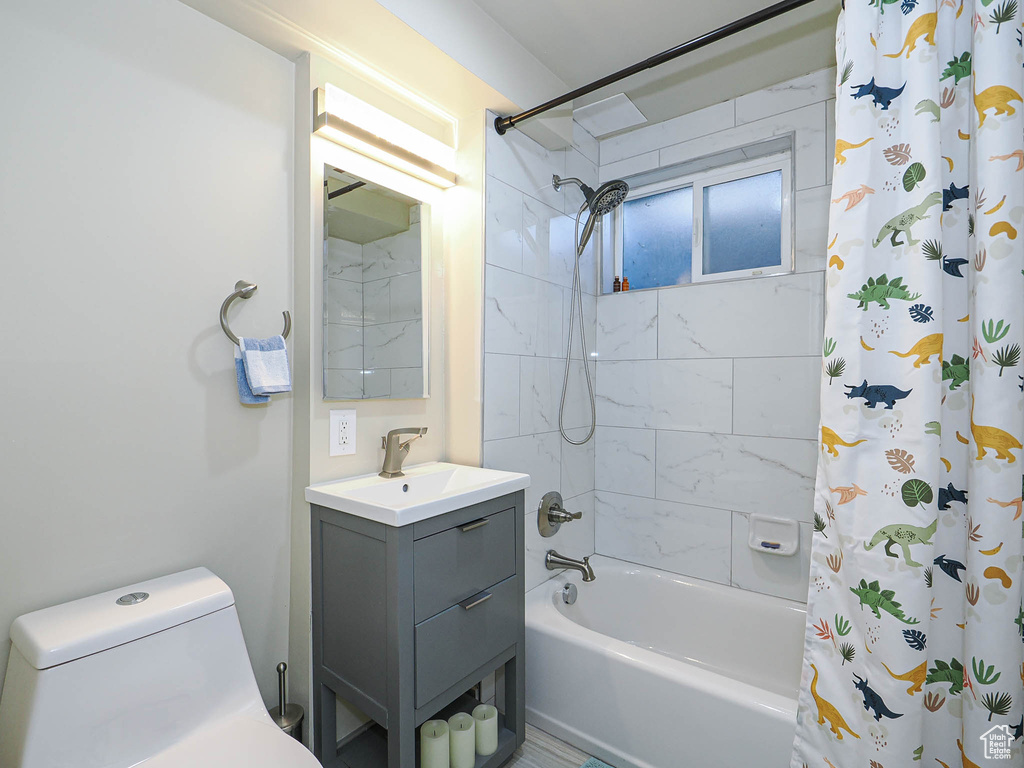 Bathroom featuring shower / tub combo with curtain, vanity, and toilet