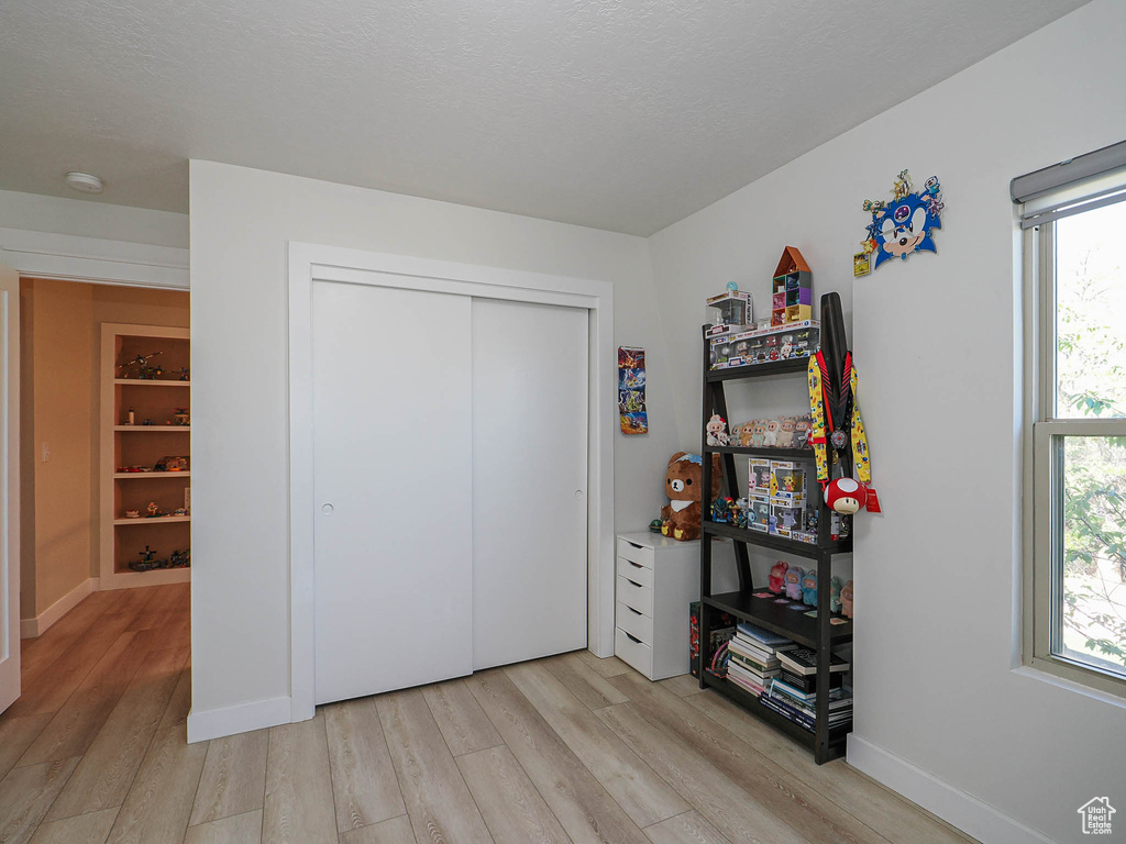 Bedroom with light wood-style flooring, multiple windows, and baseboards