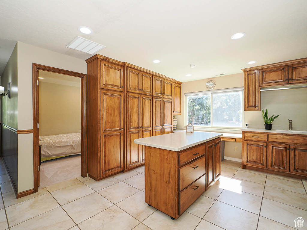 Kitchen with a sink, light countertops, brown cabinetry, and recessed lighting