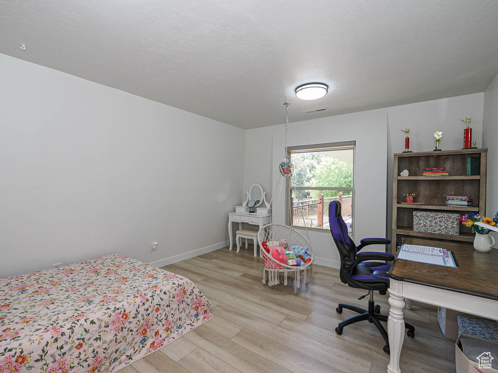 Bedroom with wood finished floors, baseboards, and an office area