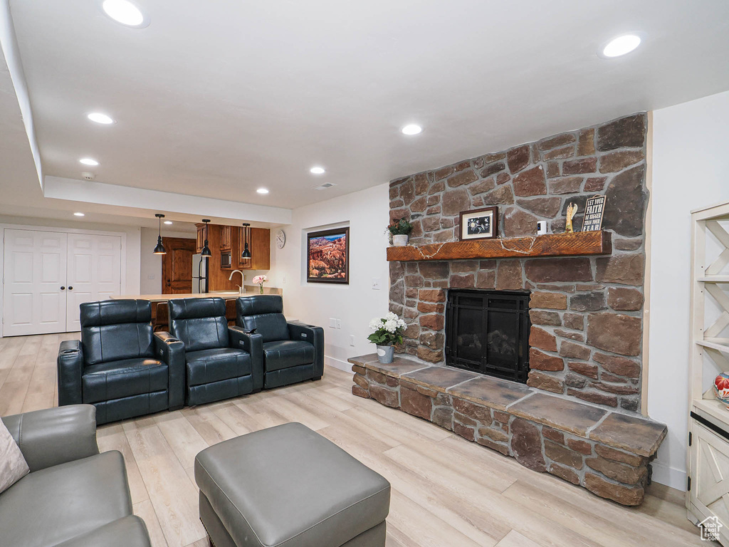 Living room featuring a stone fireplace, wood finished floors, baseboards, and recessed lighting