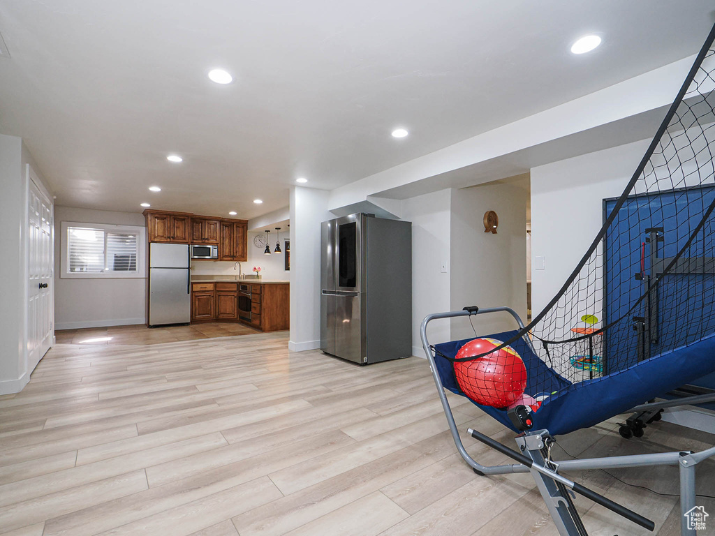Kitchen with appliances with stainless steel finishes, brown cabinetry, recessed lighting, light wood-style flooring, and baseboards