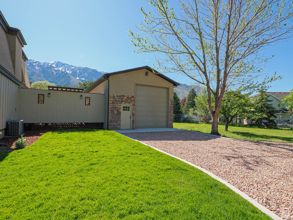 View of front of house with gravel driveway, stone siding, a mountain view, a front yard, and stucco siding