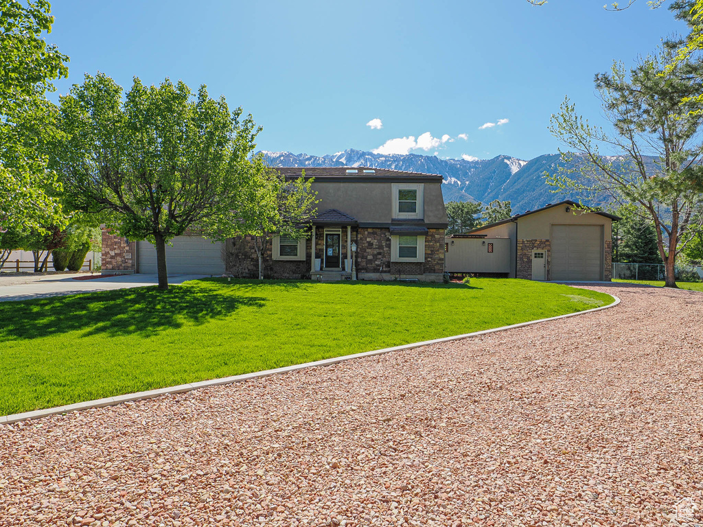 View of front of property with driveway, a garage, a mountain view, and a front lawn