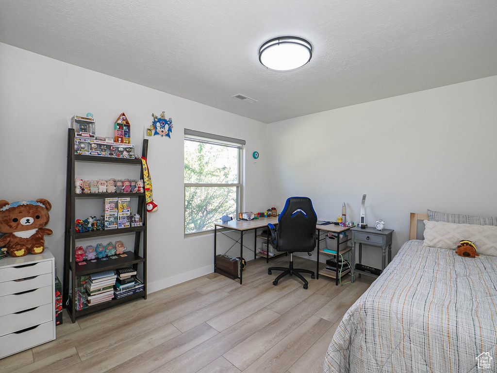 Bedroom featuring wood finished floors, baseboards, and a desk
