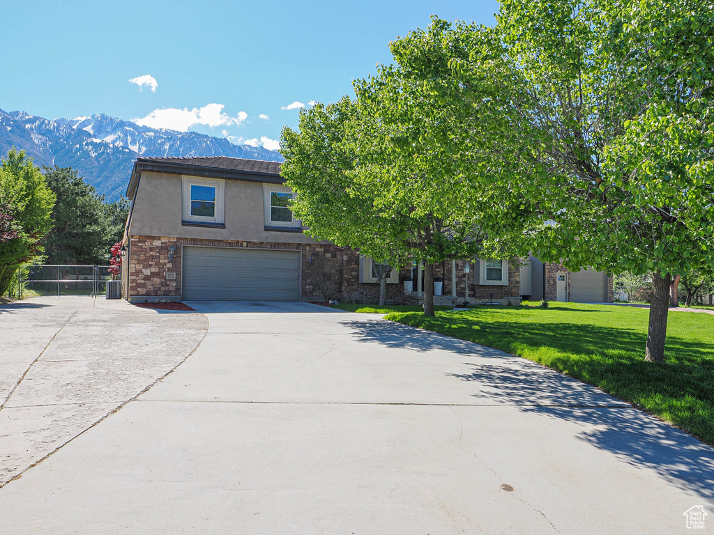 View of front of home featuring concrete driveway, a garage, a mountain view, stucco siding, and stone siding