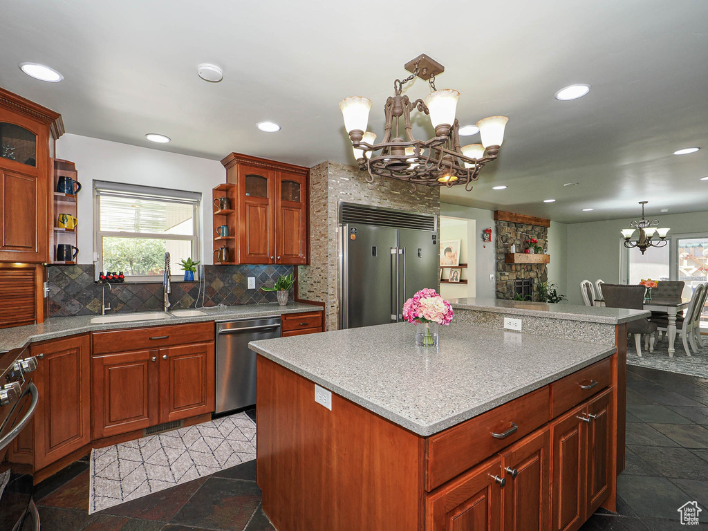 Kitchen with appliances with stainless steel finishes, a chandelier, open shelves, a sink, and backsplash