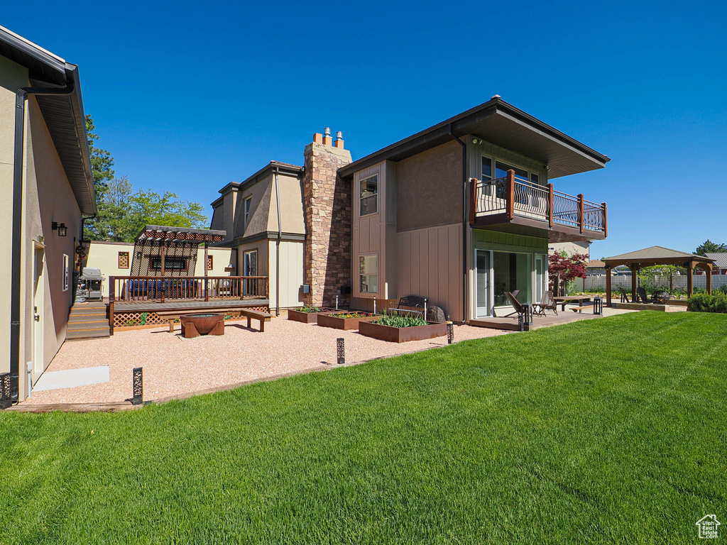 Back of house with a patio area, a gazebo, a yard, and a balcony