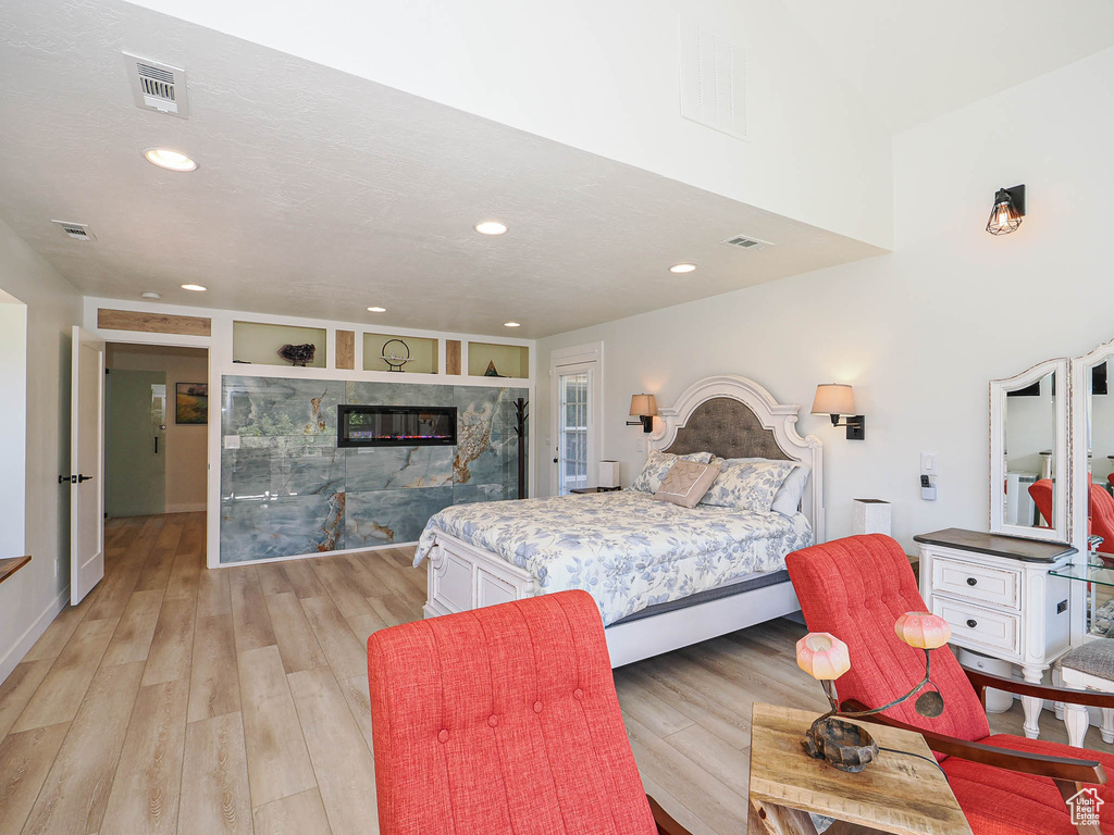 Bedroom featuring recessed lighting, light wood-style flooring, and a multi sided fireplace