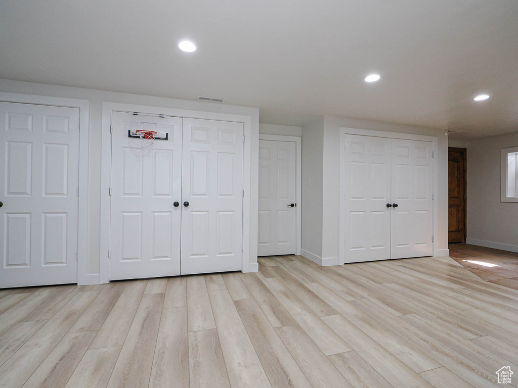 Unfurnished bedroom with multiple closets, baseboards, light wood finished floors, and recessed lighting