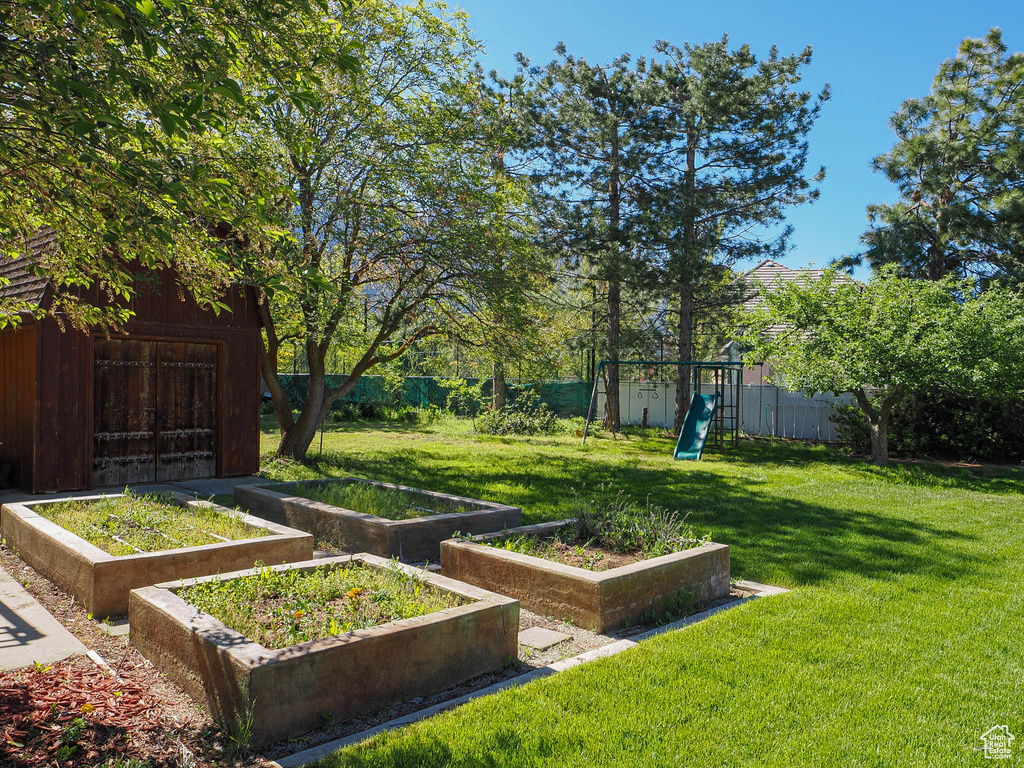 View of yard with a playground, a garden, and an outbuilding