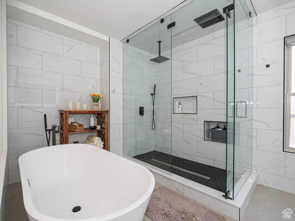 Bathroom featuring a freestanding tub, a shower stall, and tile walls