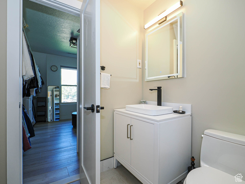 Half bathroom featuring toilet, vanity, and wood finished floors