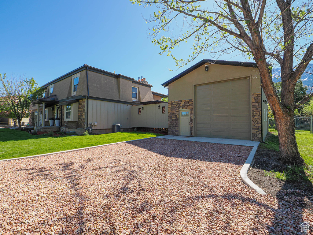 View of front of house with gravel driveway, stone siding, and a garage