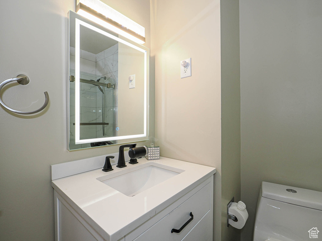 Bathroom featuring vanity, toilet, and a shower