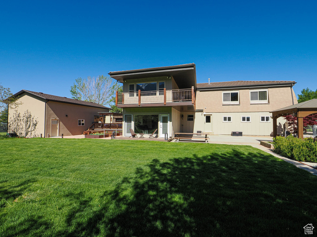 Rear view of house featuring a balcony, a lawn, a gazebo, and a patio